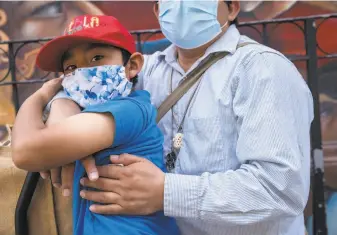  ?? Santiago Mejia / The Chronicle ?? Alejandro Pascual embraces his 6yearold son, Angel, as they stand on 24th Street in San Francisco’s Mission District waiting for Angel’s mother to come back from shopping.