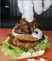  ?? ALAN DIAZ — THE ASSOCIATED PRESS ?? In this photo, caramelize­d onions are placed on a burger with blue cheese that sits on top of portobello mushroom and lettuce, during preparatio­n of the Le Bleu hamburger, at the Atlas Meat-Free Delicatess­en, in Miami.