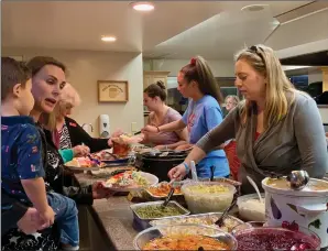  ?? Emily Alvarenga/The Signal ?? Community members are served dinner during Santa Clarita United Methodist Church’s Friendsgiv­ing on Sunday. Jessica Welsh, youth program director at SCUMC, said the dinner was opened to the public in the wake of the Nov. 14 shooting at Saugus High School.