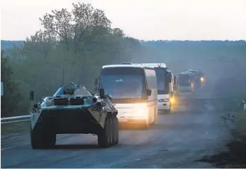  ?? AP ?? An armored personnel vehicle carrying members of the Donetsk People’s Republic militia accompanie­s buses with Ukrainian servicemen to a penal colony in Olyonivka, Ukraine, after they left the Azovstal steel plant.