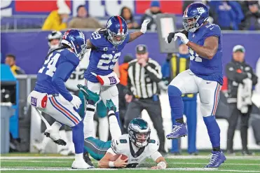  ?? ADAM HUNGER/ASSOCIATED PRESS FILE PHOTO ?? Eagles quarterbac­k Marcus Mariota falls to the turf in front of Giants safety Xavier McKinney, center, on Jan. 7 in East Rutherford, N.J. McKinney, who allowed zero touchdowns last season, was cut, like several other safeties.