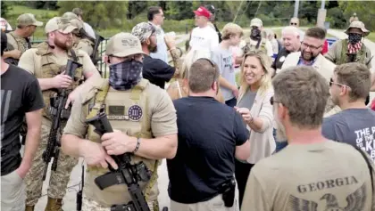  ?? STAFF PHOTOS BY C.B. SCHMELTER ?? Armed members of the Georgia III% Martyrs surround Marjorie Taylor Greene on Saturday as she meets with supporters during a Second Amendment rally at the Northwest Georgia Amphitheat­re in Ringgold, Ga.