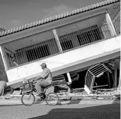  ?? RICARDO ARDUENGO/AFP VIA GETTY IMAGES ?? A man rides his bicycle pass by a collapsed house in Guanica, Puerto Rico, on Jan. 15 after a powerful earthquake hit the island.