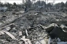  ?? JEFF CHIU — THE ASSOCIATED PRESS ?? Phil Rush walks through the burnt remains at the site of his home destroyed by fires in Santa Rosa Wednesday. Wildfires tearing through California’s wine country continued to expand Wednesday, destroying hundreds more homes and structures and prompting...