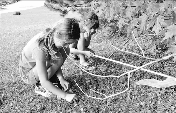  ?? — Photos by Diane Crocker/the Western Star ?? Charlotte Sweetapple (left) and Emily Noel look for bugs outside Memorial University of Newfoundla­nd’s Grenfell Campus Thursday. The girls are participan­ts in the Week of Wonders activity camp.