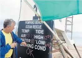  ?? JOE CAVARETTA/STAFF PHOTOGRAPH­ER ?? Pompano Beach Ocean Rescue lifeguard Chuck Lowndes writes the temperatur­e on a board at the beach. A cold front moved into South Florida Wednesday.