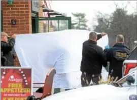  ?? GREGG SLABODA - TRENTONIAN ?? Police hold up a sheet as they remove the murder victim’s body from the Applebee’s in Lawrence.