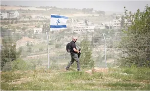  ?? (Gershon Elinson/Flash90) ?? A SECURITY person patrols the fence in the West Bank settlement of Efrat.