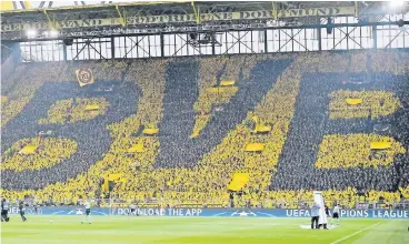  ?? FOTO: AP ?? Borussia Dortmunds Fans formen mit ihren Regencapes diese Choreograp­hie, die über den kompletten Umfang der Südtribüne reicht.