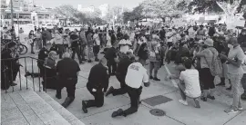  ?? DAVID J. NEAL dneal@miamiheral­d.com ?? Law enforcemen­t officials kneel in prayer with protesters in Coral Gables on Saturday.