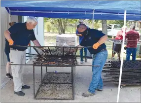  ?? Westside Eagle Observer/MIKE ECKELS ?? A pair of chicken flippers removes the top grill from a rack to reveal perfectly cooked chicken halves during the August 7, 2021, Decatur Barbecue. Volunteers from the community start cooking chicken in the early morning to ensure the birds are cooked and ready for their public debut around 10 a.m.