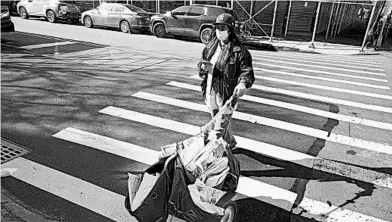  ?? MARK LENNIHAN/AP ?? A postal worker wears a mask and gloves as she delivers the mail March 26 in the Brooklyn borough of New York.