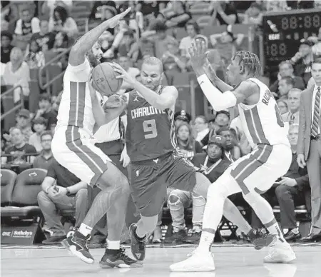  ?? JOHN MCCALL/SUN SENTINEL PHOTOS ?? James Johnson and Josh Richardson of the Heat try to stop Hornets guard Tony Parker in the second half Sunday at AmericanAi­rlines Arena in Miami.