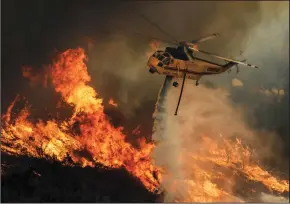  ?? IRFAN KHAN/LOS ANGELES TIMES ?? A helicopter drops water on raging flames at North Main Divide along Ortega Highway in Lake Elsinore on Friday.