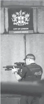  ??  ?? A police officer looks through his weapon Saturday on London Bridge. Emergency personnel treat wounded people on the bridge.
