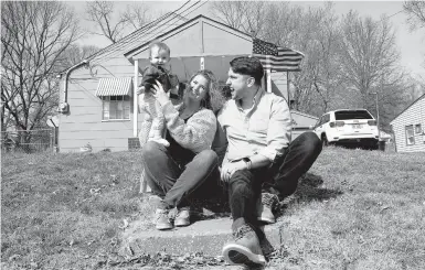  ?? CHARLIE RIEDEL/AP ?? Logan DeWitt with his wife, Mckenzie, and daughter Elizabeth sit on the steps leading to their home Monday in Kansas City, Kansas. Their financial situation during the pandemic was complicate­d with Elizabeth’s birth nine months ago and a job loss.