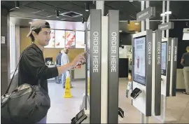  ?? CHARLES REX ARBOGAST — ASSOCIATED PRESS ?? Brandon Alba orders food at a self-service kiosk at a McDonald’s restaurant in Chicago.