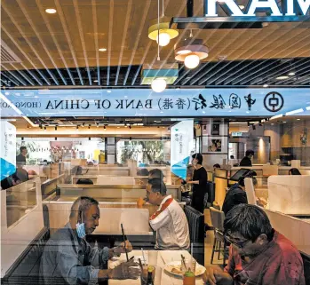  ?? LAM YIK FEI/THE NEW YORK TIMES ?? Hong Kong is seeing coronaviru­s cases on par with its summer wave. Above, diners eat at a restaurant in Hong Kong with dividers between booths.