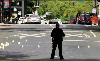  ?? RICH PEDRONCELL­I — THE ASSOCIATED PRESS ?? A Sacramento police officer stands near a field of evidence markers after a mass shooting in the city on Sunday. California lawmakers are considerin­g ways to stem the acquisitio­n and use of illegal firearms.