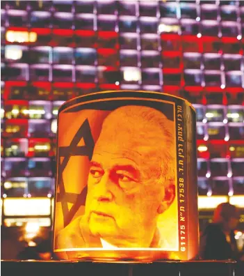  ?? JACK GUEZ / AFP VIA GETTY IMAGES ?? A portrait of former Israeli Prime Minister Yitzhak Rabin at Rabin Square in Tel Aviv last week,
during a 25,000-candle vigil ahead of the 25th anniversar­y of his assassinat­ion.