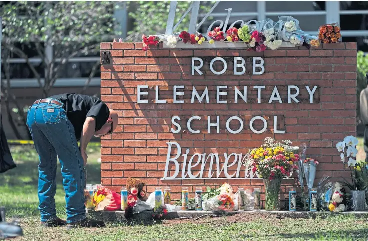  ?? ?? HEARTBREAK: A law enforcemen­t officer lights a candle outside Robb Elementary School where 19 children and two teachers were shot dead.