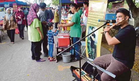  ?? PIC BY MOHD KHIDIR ZAKARIA ?? Noramry Mohamad playing his flute at the Taman Politeknik Ramadan bazaar in Port Dickson to collect donations for orphans.