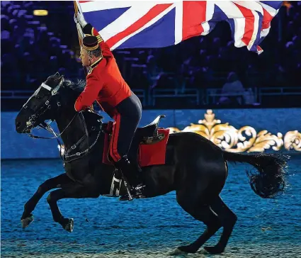  ??  ?? Flying the flag: Galloping across the arena on a glossy black steed, this horseman leads the celebratio­ns