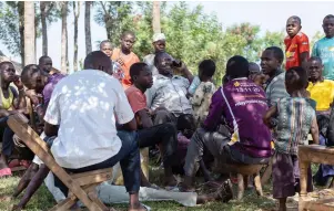  ?? ?? Hasahya (centre) smiles as he speaks on a mobile phone while sitting with some of his children and grandchild­ren.