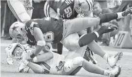  ?? CHARLES TRAINOR JR/TNS ?? Dolphins quarterbac­k Ryan Tannehill is tackled by the Cowboys on Sunday in Miami.