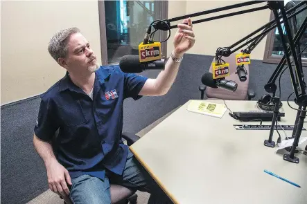  ?? QC PHOTO BY BRANDON HARDER ?? Grant Biebrick, program director for CKRM, jokes around while adjusting one of the microphone­s in the booth used for the Sports Cage broadcast at Harvard Broadcasti­ng’s Rose Street office.