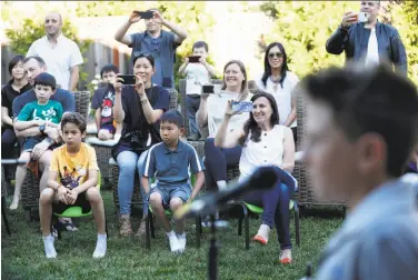  ?? Photos by Scott Strazzante / The Chronicle ?? Lydia Mazzie (right) sits in the front row to watch the kid band Good Stuff play in her backyard for other parents and their children. She says she has enjoyed watching her son’s passion for music develop.