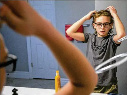  ?? DANIEL SHULAR/ST. LOUIS POST-DISPATCH/TNS ?? Lucas Desroche, 11, styles his mullet Dec. 18 before a family Christmas party in Oakville, Missouri. Lucas has been growing his mullet for more than a year, and has influenced baseball and hockey teammates to grow their own.