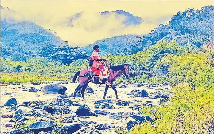  ?? Picture: JONACANI LALAKOBAU ?? A woman crosses the Wainiagai River on horseback. The Delai Nava hills are visible in the background.