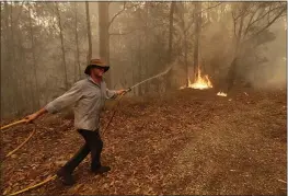  ?? RICK RYCROFT — THE ASSOCIATED PRESS ?? A man uses a water hose to battle a fire near Moruya, Australia, on Saturday.