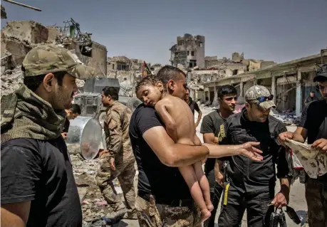  ?? (The New York Times) ?? Ivor Prickett Durante la battaglia di Mosul nel 2017 un bambino senza vestiti, che sembra quasi addormenta­to, viene tenuto in braccio da un uomo sospettato di essere un miliziano dell’isis e circondato da soldati delle truppe irachene. La scena è in...