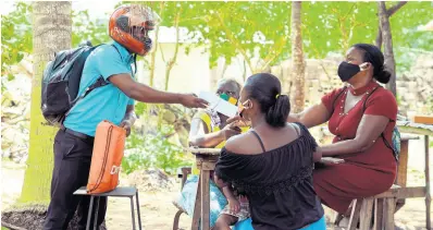  ?? CONTRIBUTE­D ?? Residents of Little Bay in Westmorela­nd collect their children’s schoolwork from Keron King, principal of Little Bay Infant and All-Age School.