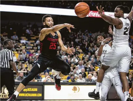  ?? Willie J. Allen Jr. / Associated Press ?? UH guard Galen Robinson Jr., left, whips a pass past Central Florida's Xavier Grant. Robinson had seven assists in Thursday’s win.