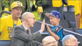  ?? THEARON W. HENDERSON — GETTY IMAGES ?? NBA Commission­er Adam Silver give a high-five to a young fan at a Warriors game.