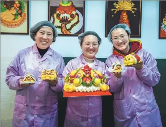  ?? LIU WEIFANG / FOR CHINA DAILY ?? Qu Baole (middle) and her colleagues display dragon-themed bobo buns they made in a factory in the Fushan district of Yantai, Shandong province.