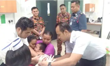  ??  ?? Tiong (right) and Bomba personnel watch as Alvincent undergoes a checkup at the Teng Bukap clinic.