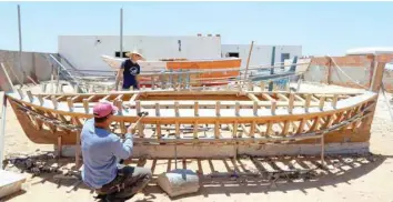  ?? — AFP ?? Fishermen work on a wooden boat on the Mediterran­ean coast in Tunisia’s Kerkennah Islands off Sfax.