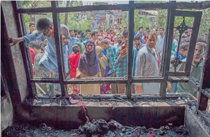  ?? AP ?? kashmiri villagers inspect a house damaged during a gun battle between soldiers and suspected militants in hakripora on tuesday. —