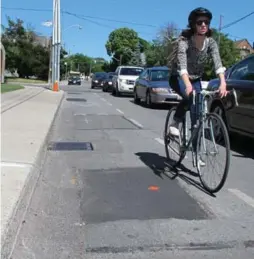  ?? JACK LAKEY/TORONTO STAR ?? A cyclist steers around a utility cut in the bike lane on the north side of Annette St., just west of Medland St. The cuts on the north side were recently filled.