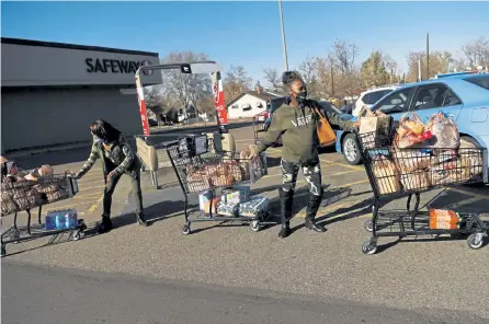  ?? Rachel Ellis, The Denver Post ?? Cynthia Winston, left, and daughter Tiffany Winston work together to haul three carts of groceries to their car Thursday after shopping at the Safeway on 44th Street in Denver.