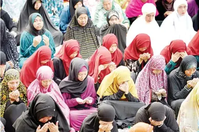  ??  ?? DEEP SORROW – Female Muslim residents of Marawi City in traditiona­l ‘hijab’ clothing, who are currently staying at evacuation centers in Iligan City, pray during Eid’l Fitr Sunday that was bereft of the usual joyous celebratio­n that comes with the end...