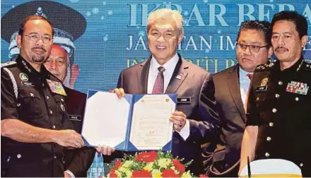  ?? BERNAMA PIC ?? Deputy Prime Minister Datuk Seri Dr Ahmad Zahid Hamidi showing the corruption-free pledge signed by Immigratio­n Department director-general Datuk Seri Mustafar Ali (left) in Putrajaya yesterday. With them are Deputy Home Minister Datuk Nur Jazlan...