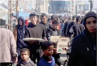  ?? AFP PHOTO ?? NOWHERE ELSE TO GO
Palestinia­ns carrying food supplies walk through a crowded street inside a refugee camp in the southern Gazan city of Rafah on Monday, Feb. 26, 2024.