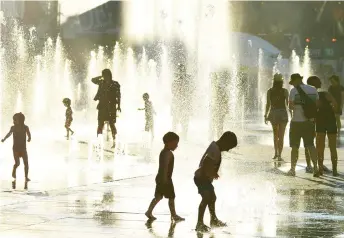  ?? Photo — AFP file ?? Children play in the water fountains at the Place des Arts in Montreal, Canada on a hot summer day.