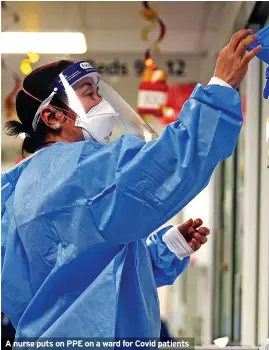  ?? ?? A nurse puts on PPE on a ward for Covid patients