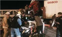  ??  ?? Paramedics help a driver after firefighte­rs helped him out of his wrecked vehicle.